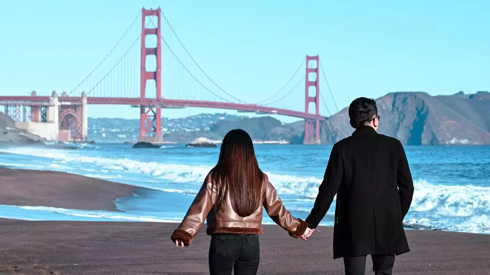 Casal de mãos dadas em 贝克海滩 com a ponte Golden Gate ao fundo 