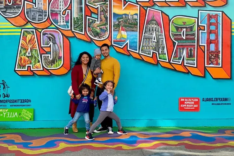 Une famille posant pour une photo devant une fresque murale de San Francisco