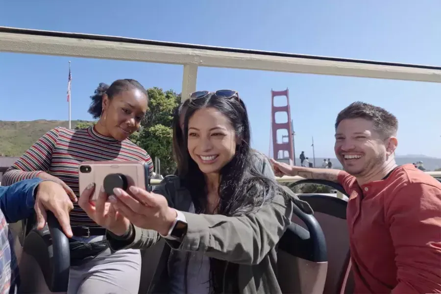 Um grupo de visitantes tira uma selfie em um passeio de ônibus perto da Ponte Golden Gate. 加州贝博体彩app.