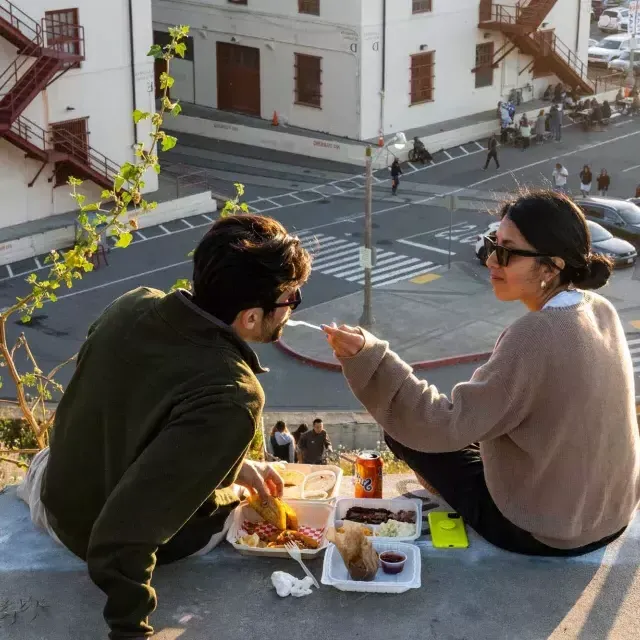 一对夫妇在贝博体彩app梅森堡中心的户外晚餐。. 女人给她的伴侣一些食物.