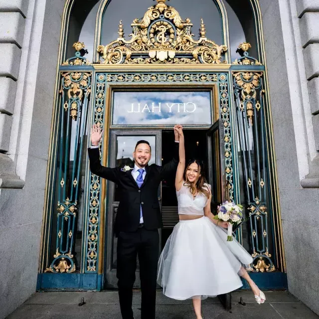 Couple posing in front of city hall after wedding